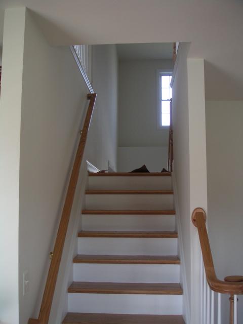 Looking up back half of stairs, stairs continue down the other side into foyer and up to the right to the second floor